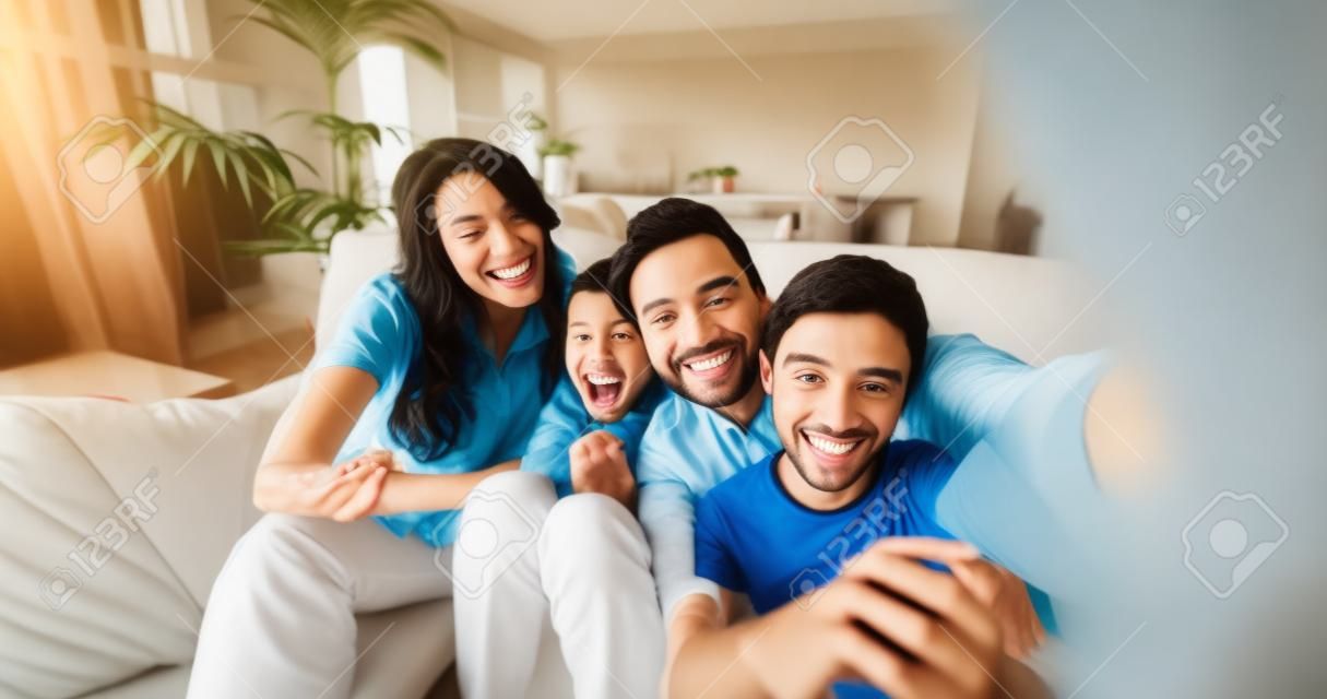 Porträt einer glücklichen Familie, die in Zeitlupe Selfie im Wohnzimmer macht. Konzept der Kommunikation, Verbindung, Technologie, Lebensstil, Soziales, Familie.
