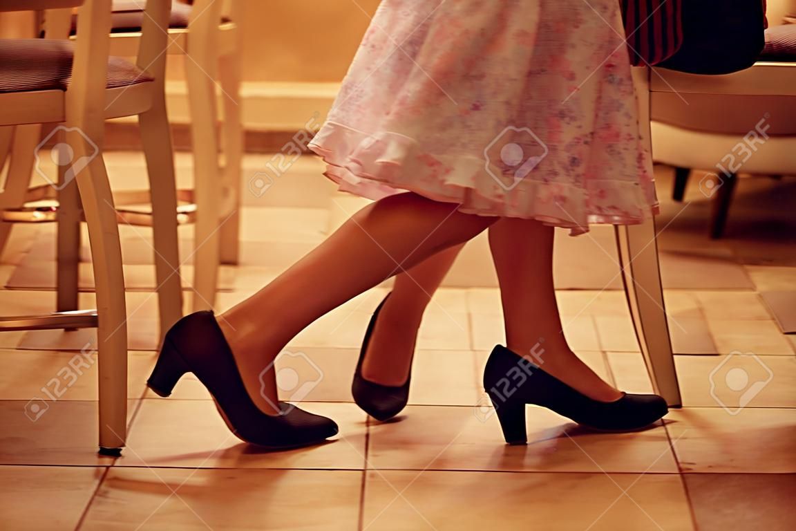 Jambes d'une fille jouant avec des mères chaussures