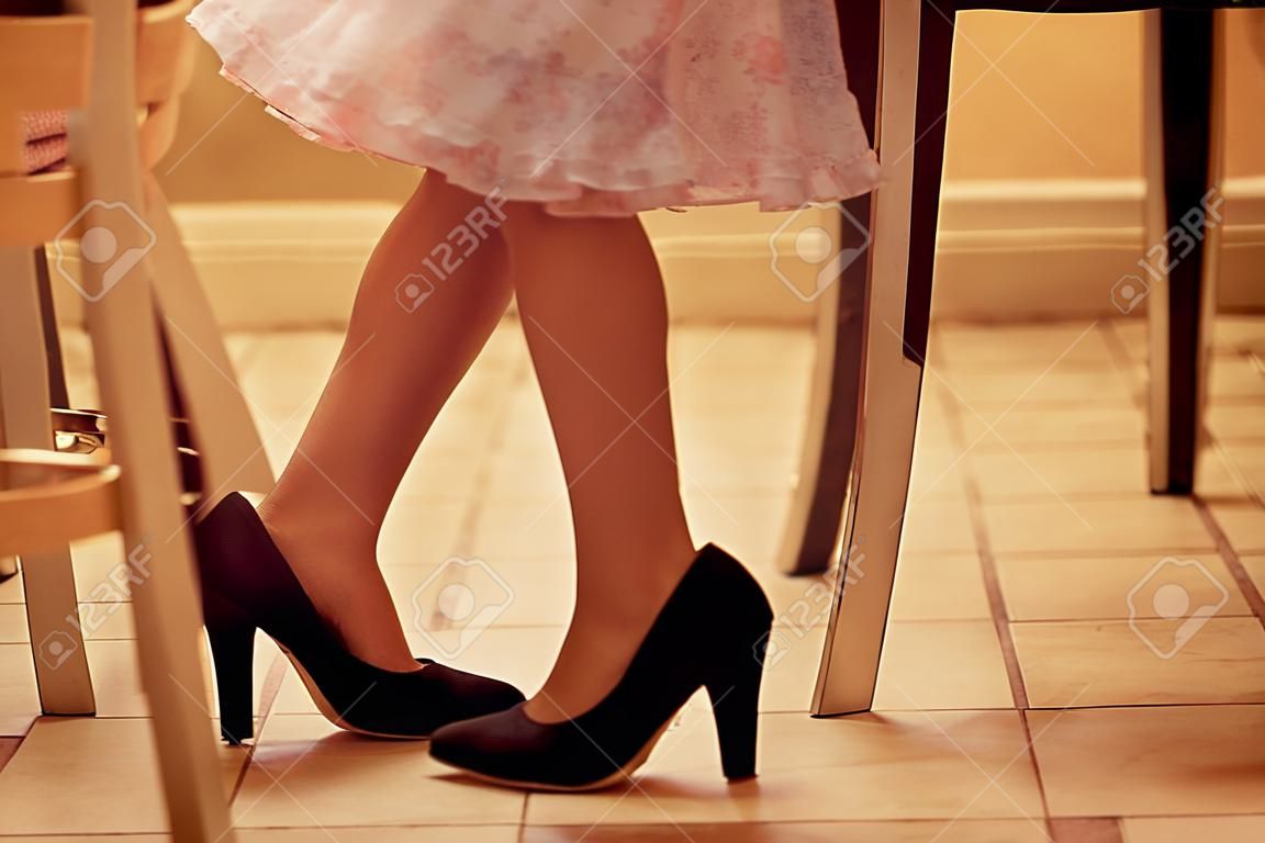 Legs of a girl playing with mothers shoes