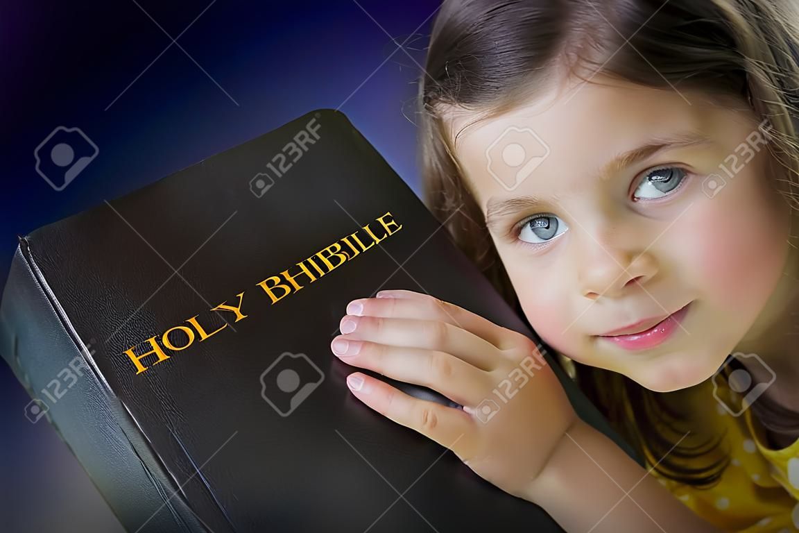 Ritratto di una bella bambina che tiene Sacra Bibbia. Bibbia chiusa