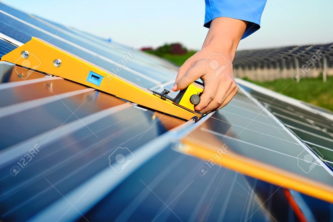 Ingegnere uomo in uniforme che lavora su energia solare campo di pannelli solari produzione di energia pulita energia verde