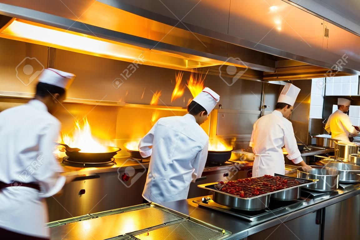 Chef en cuisine de restaurant au cuisinière avec poêle, faire flamber sur les denrées alimentaires