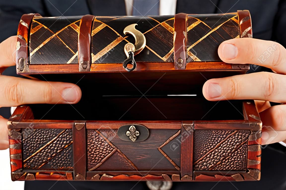 Business man hand holding old antique brown wood treasure chest or box white isolated
