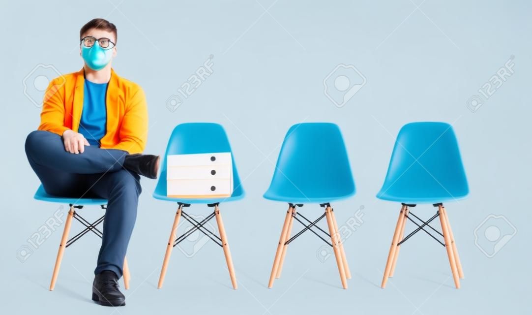 I am ready to plunge into new company. Cheerful young man is sitting on chair and waiting for a job interview. He is wearing a diving mask and looking at camera seriously