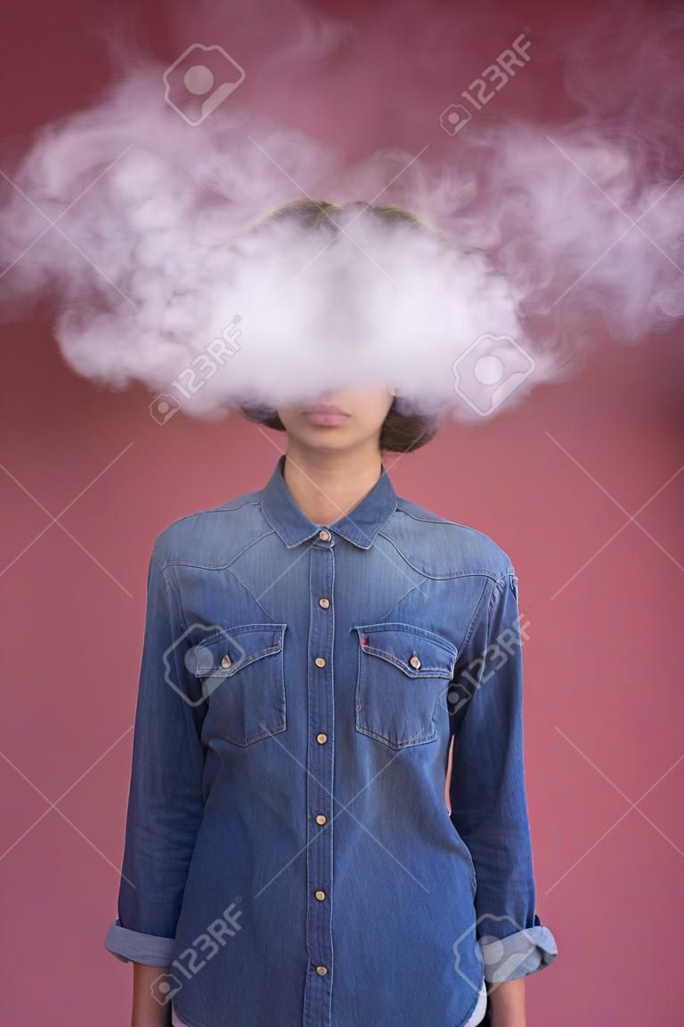Ernsthafte junge Frau steht, während sie Rauch um ihren Kopf hat. Überschüssiges Informationskonzept. Isoliert