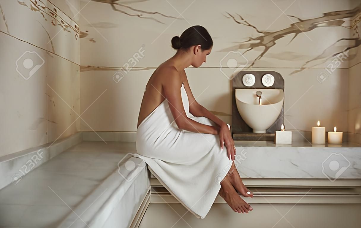 Woman in hammam. Peaceful dark haired lady showing her beautiful legs and looking calm at hammam procedure