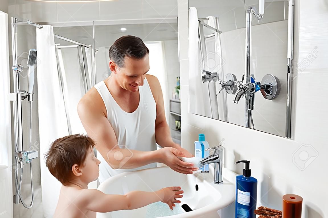 Padre e hijo se lavan las manos en el baño.