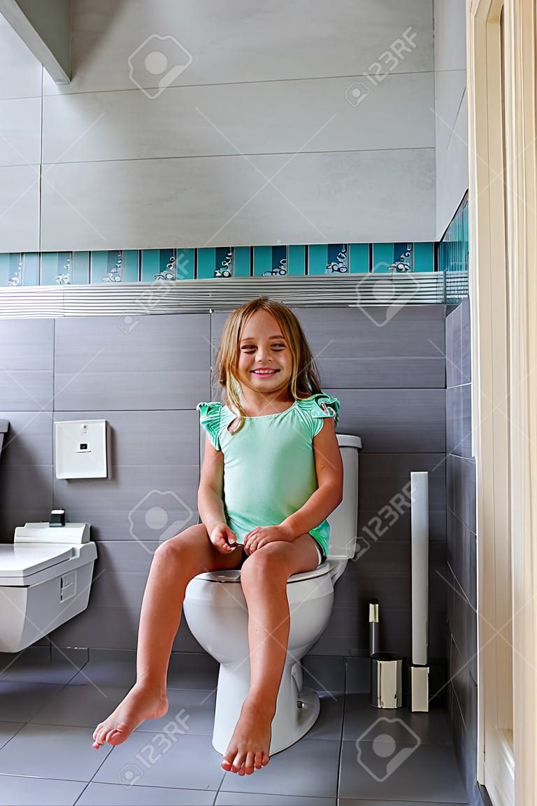 Ragazza sorridente seduta su un water in bagno