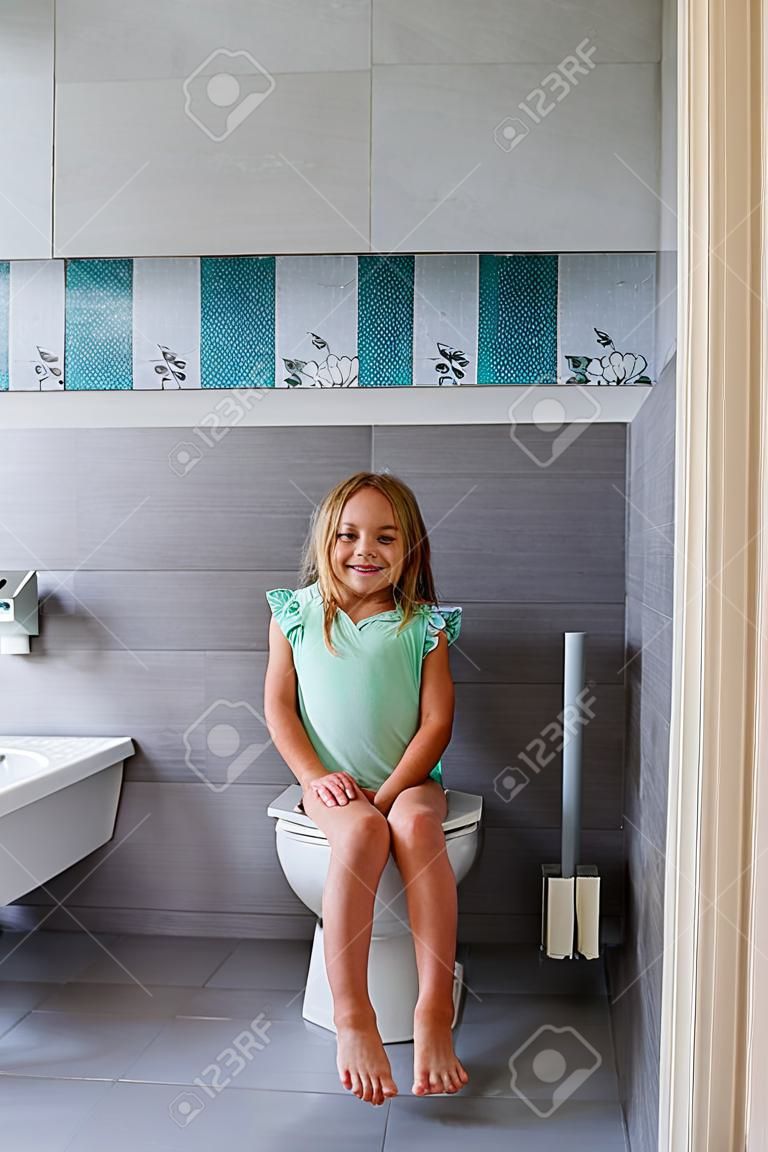 Ragazza sorridente seduta su un water in bagno
