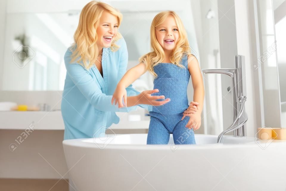 Wesoła mama w pobliżu córek w łazience