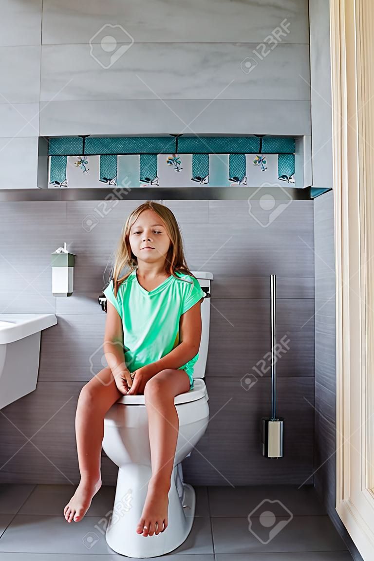 Cute girl is sitting in the toilet