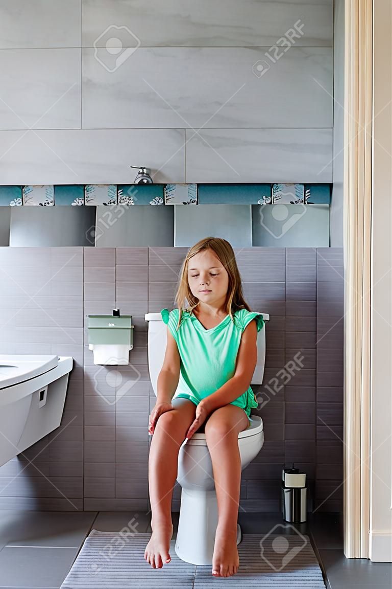 Cute girl is sitting in the toilet