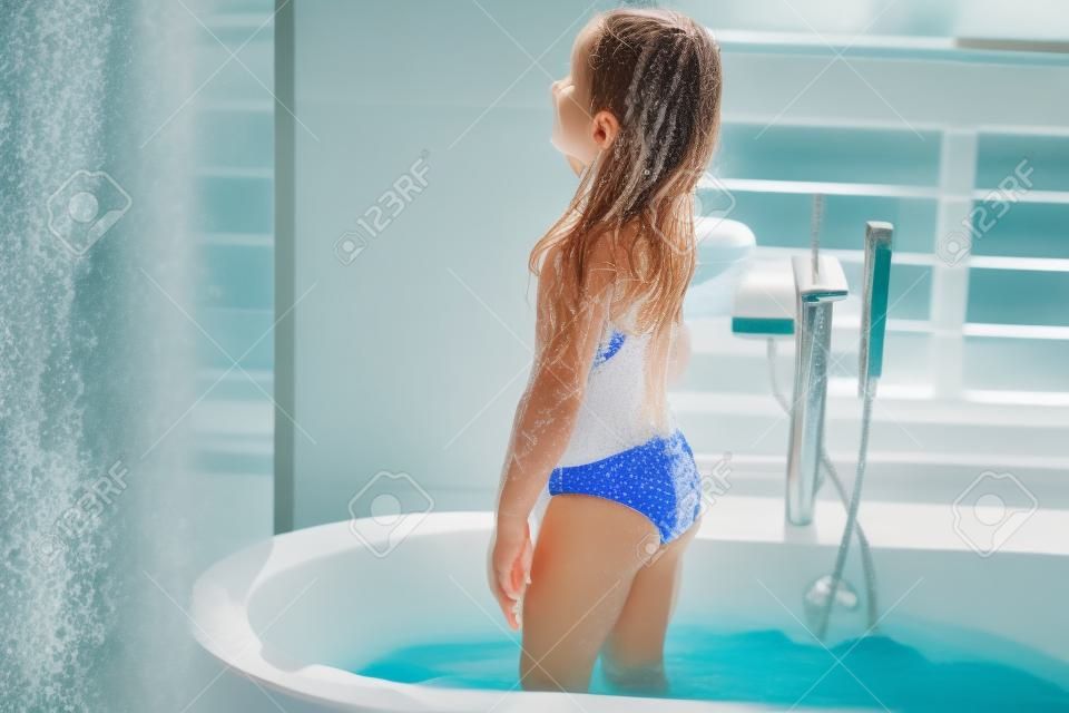 Girl in bathing suit standing in bath