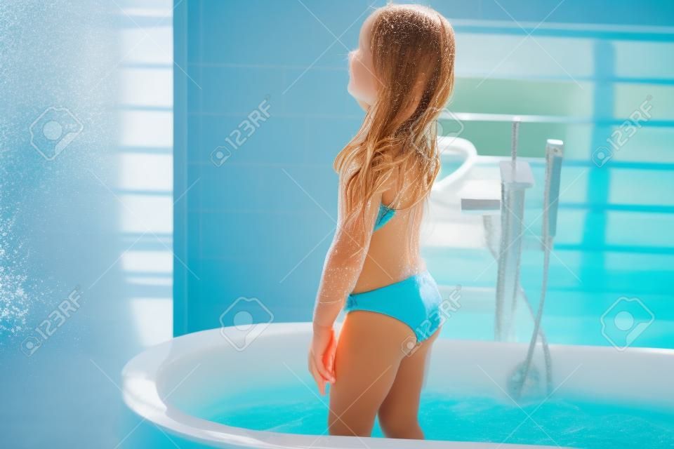 Mädchen im Badeanzug, das in der Badewanne steht