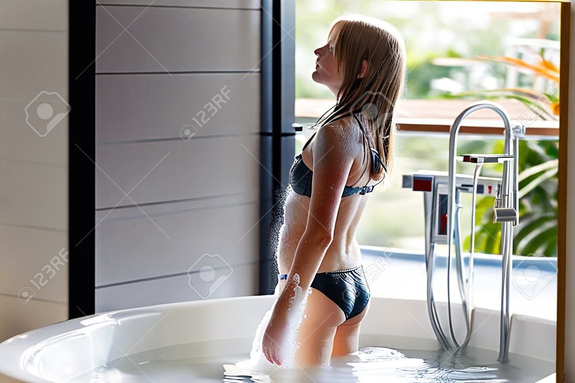 Mädchen im Badeanzug, das in der Badewanne steht