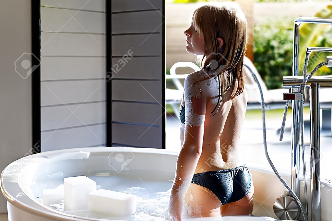 Girl in bathing suit standing in bath