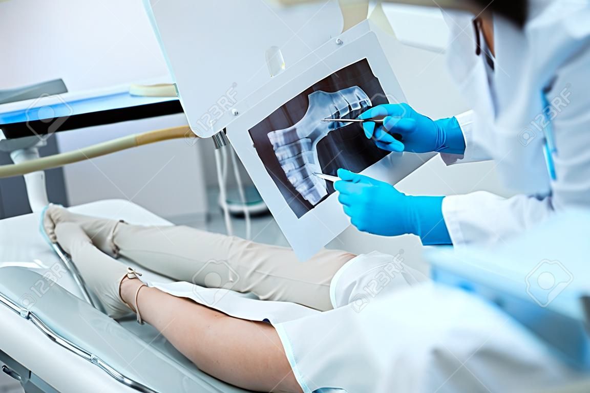 Dentist is analysing x-ray with adult woman