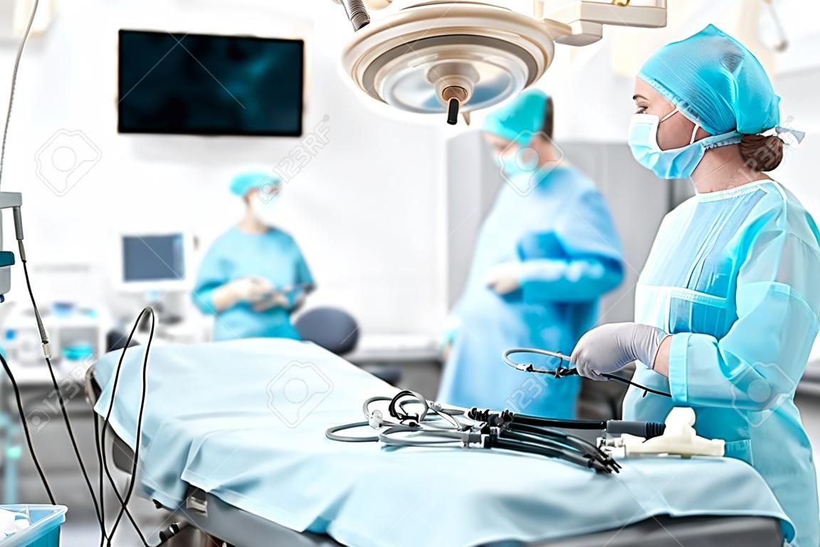 Jonge verpleegkundige met laparoscopisch instrument en kijken naar collega's