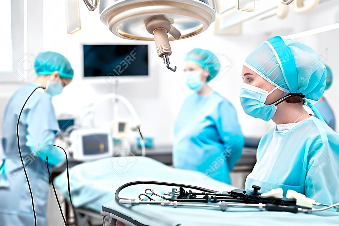 Junge Krankenschwester, die laparoskopisches Instrument hält und Kollegen ansieht
