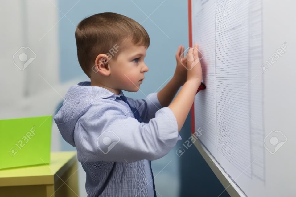Serious caucasian boy looking attentively at the whiteboard