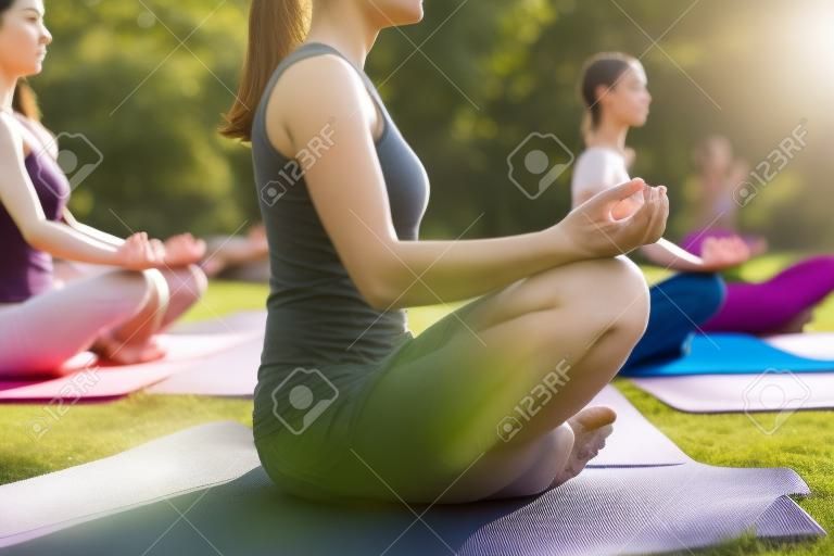 Group of people exercising on yoga mats in lotus pose