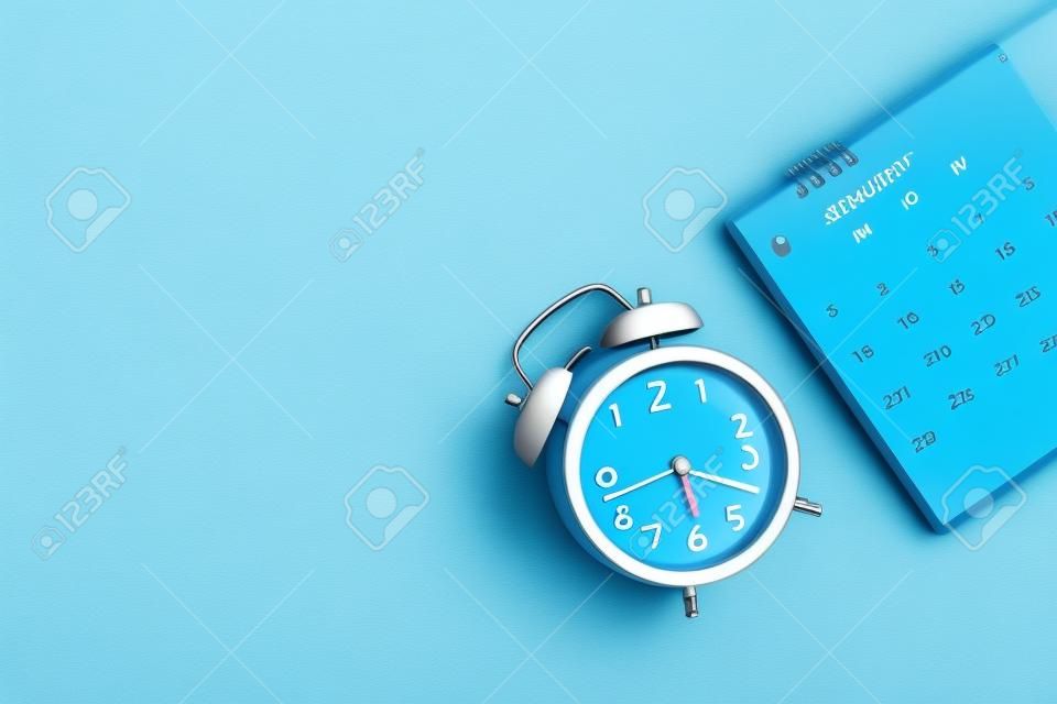 An alarm clock with calendar on blue background for the concept of time and date management.
