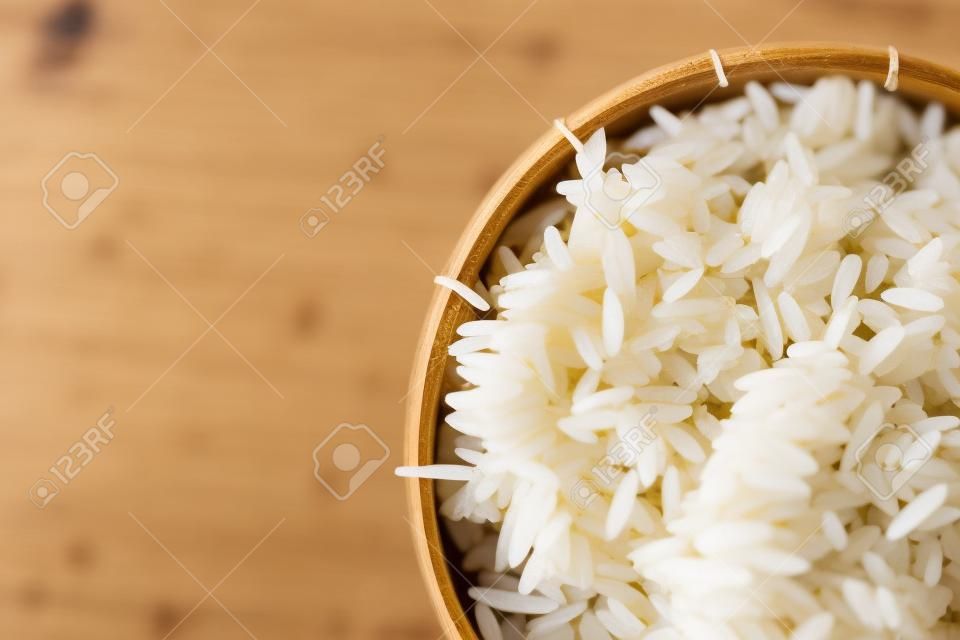 Close-up of grains of uncooked white  jasmine rice in  bamboo container . Jasmine rice is grown primarily in Thailand (Thai hom mali or Thai fragrant rice)