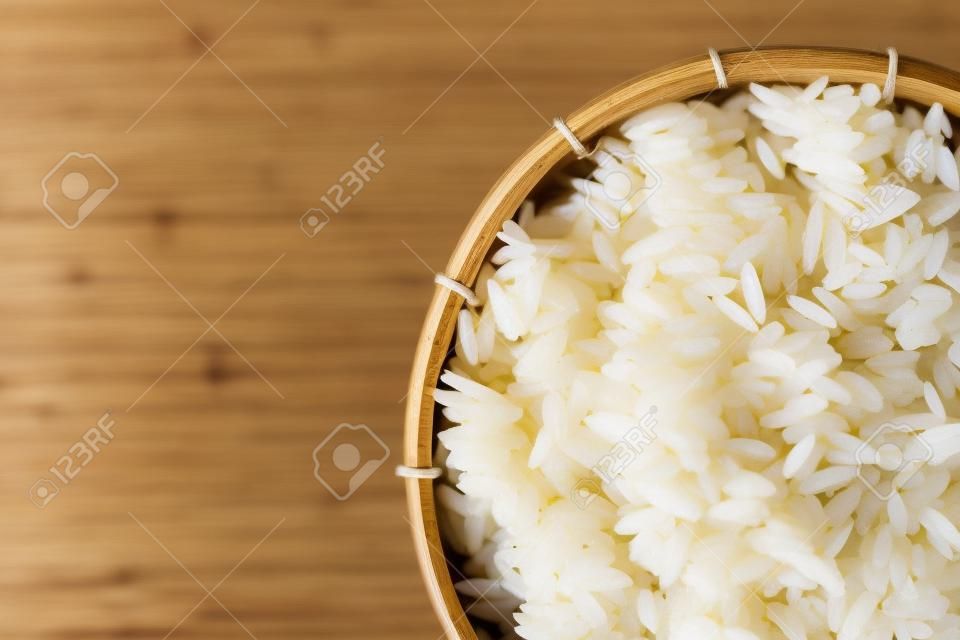 Close-up of grains of uncooked white  jasmine rice in  bamboo container . Jasmine rice is grown primarily in Thailand (Thai hom mali or Thai fragrant rice)