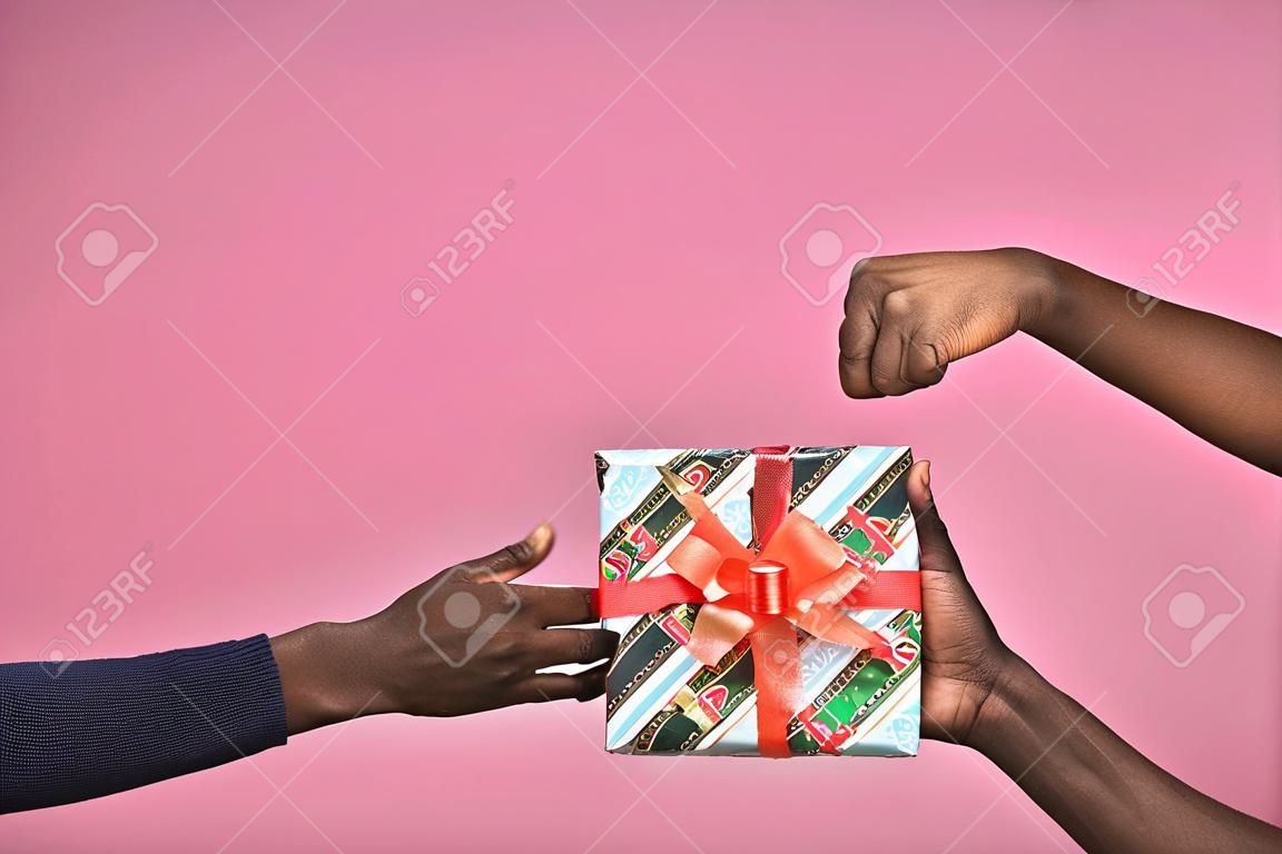 someone giving a gift box to another person, black people, hands only, doing a thumbs up