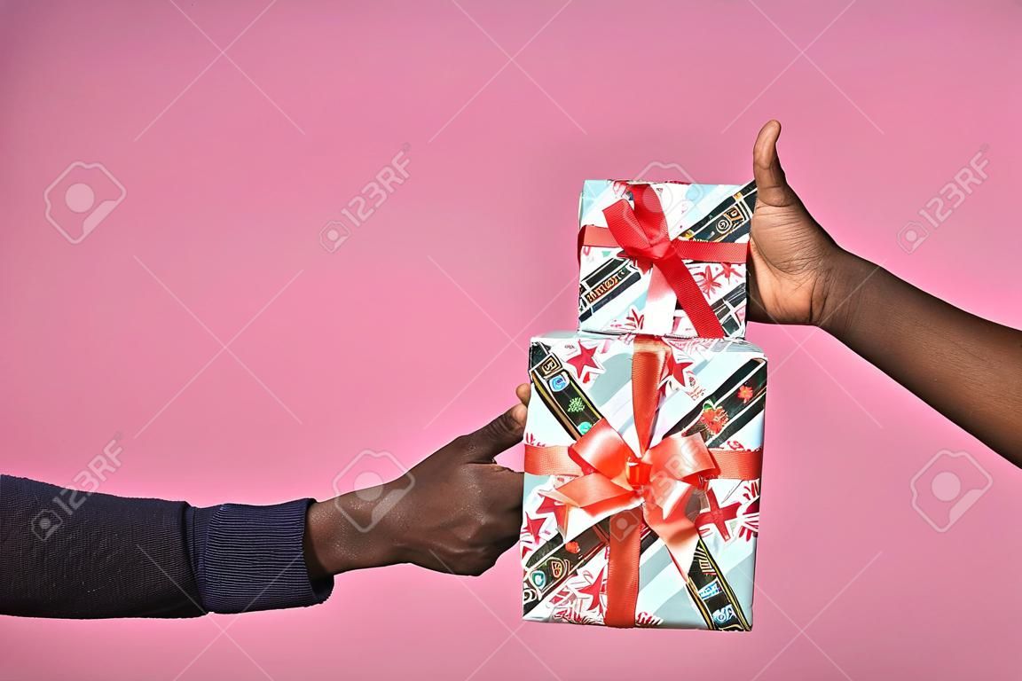 someone giving a gift box to another person, black people, hands only, doing a thumbs up