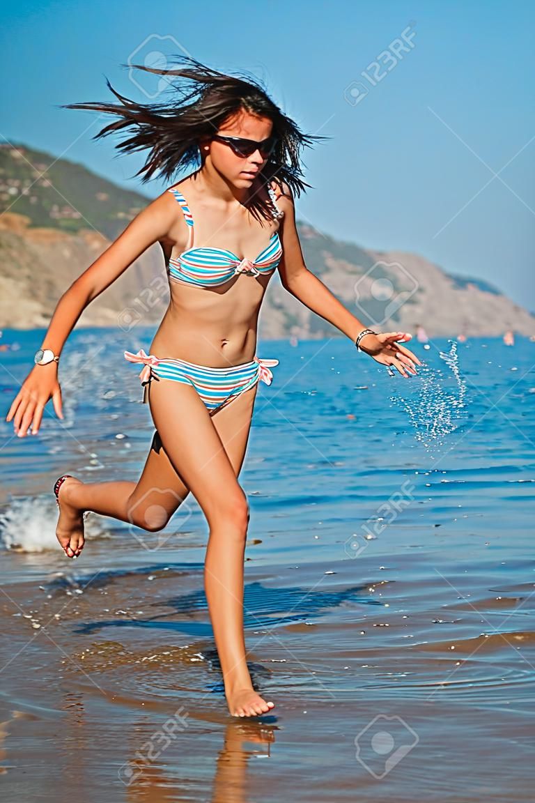 Muchacha adolescente joven que juega con las olas en la playa