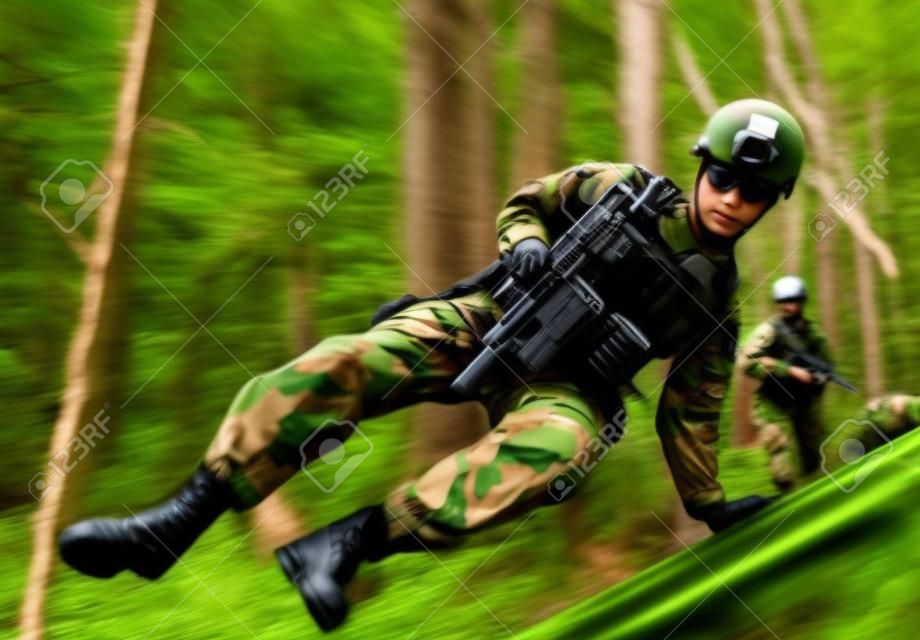 Foto van een volledig uitgeruste soldaten die springen en rennen met geweren in het bos.