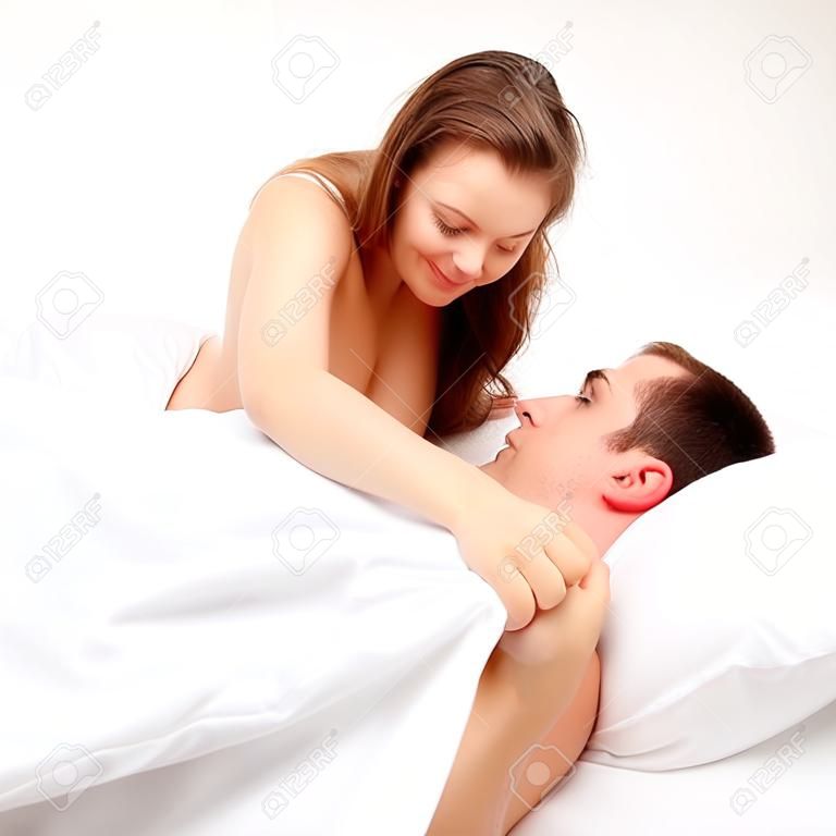 Young couple in bed, woman looking at the man's private part