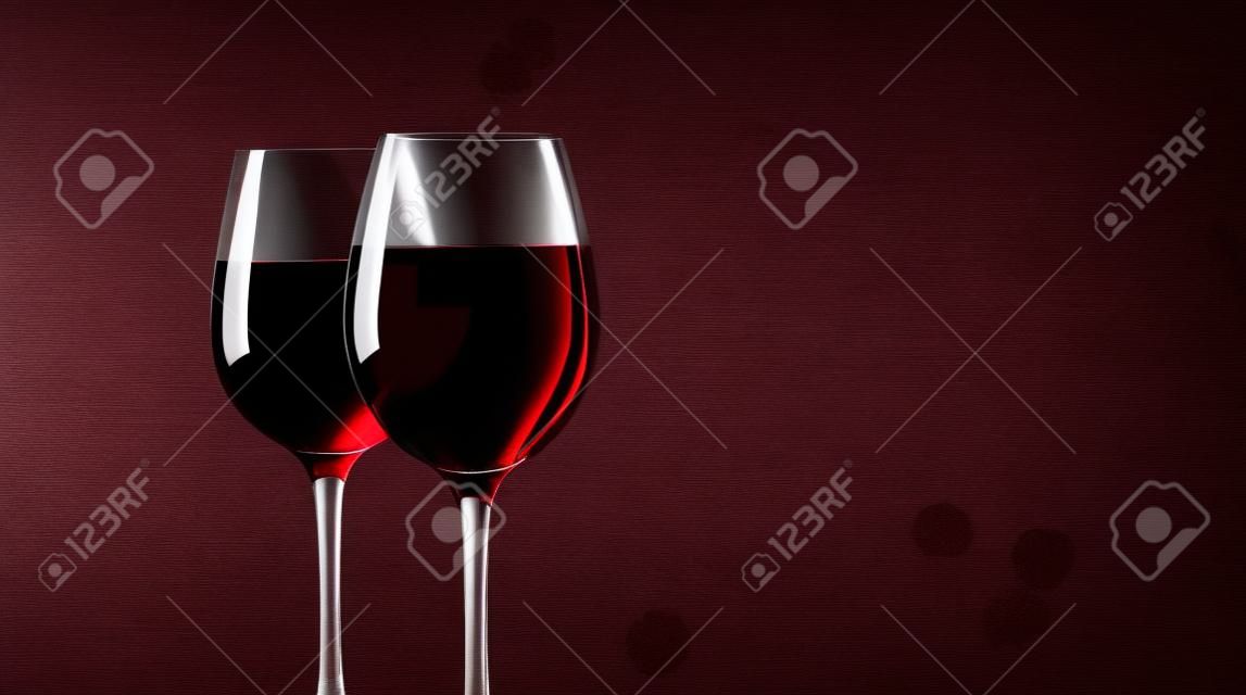 vasos con vino tinto contra del color de fondo.