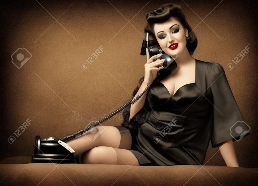 Beautiful Brunette Woman In Pin Up Style Speaking Via Vintage Phone.  Attractive Young Woman In 50s Style With Perfect Make-up And Hairstyle.  Black And White. Stock Photo, Picture and Royalty Free Image.