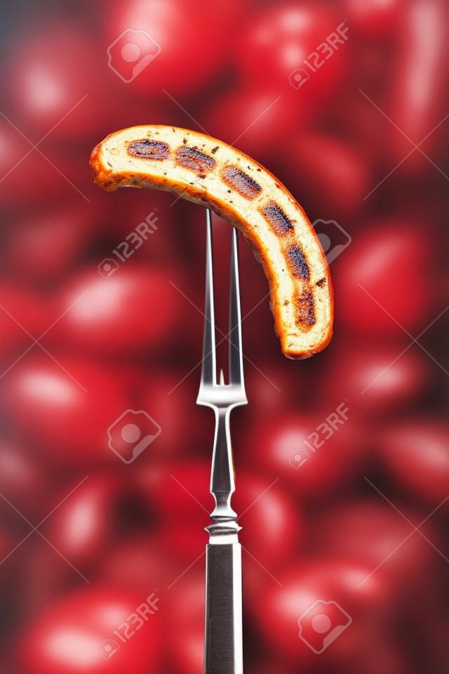Grilled Bavarian sausage on a fork. Copy space.