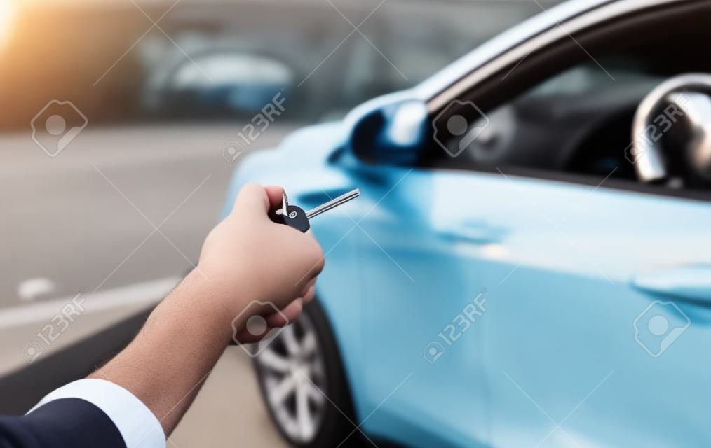 Nahaufnahme des Fahrers vor dem Auto, der Schlüssel in der Hand hält. Fahrerhände zeigen die Autoschlüssel, Fahrerhände zeigen die Schlüssel außerhalb des Fahrzeugs, Fahrzeugvermietungskonzept