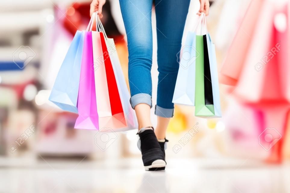 Die Beine der Frau genießen das Einkaufen im Einkaufszentrum, die Hand, die das Einkaufen hält, den Konsum kauft und einkauft, das Einkaufen im Sommer-Discounter genießt