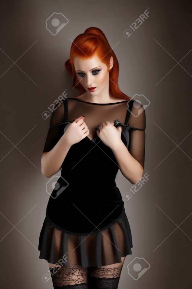 美しい赤毛の短い黒のドレスとストッキングを身に着けています。