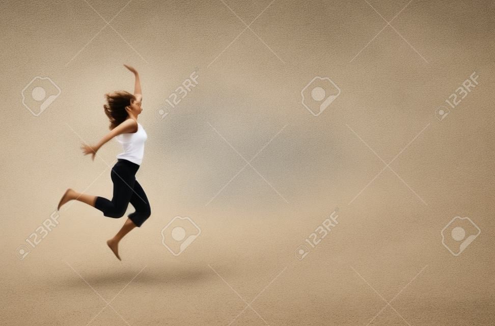 Atractive giovane donna in esecuzione e il salto in spiaggia