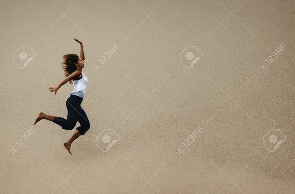 Atractive giovane donna in esecuzione e il salto in spiaggia