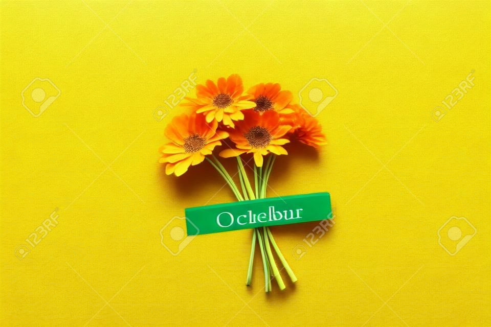 Calendar autumn month October and orange flowers on green background. Top view Flat lay. Minimal concept Hello fall. Template for your design, greeting card.