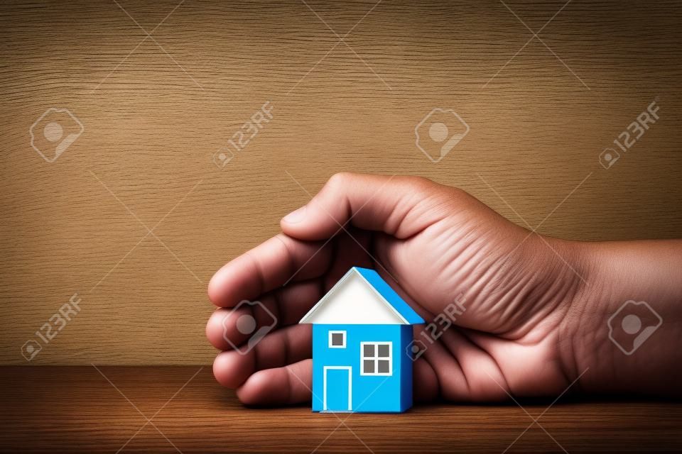 The hand covers the house. Home security concept, real estate insurance. Affordable housing. realtor service. Inviolability of private property. Preservation of the cultural architectural fund.