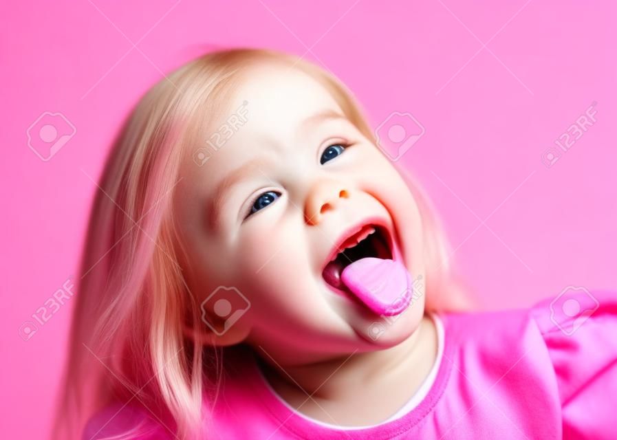 Bliska strzał dziewczynki z językiem na różowym na białym tle.