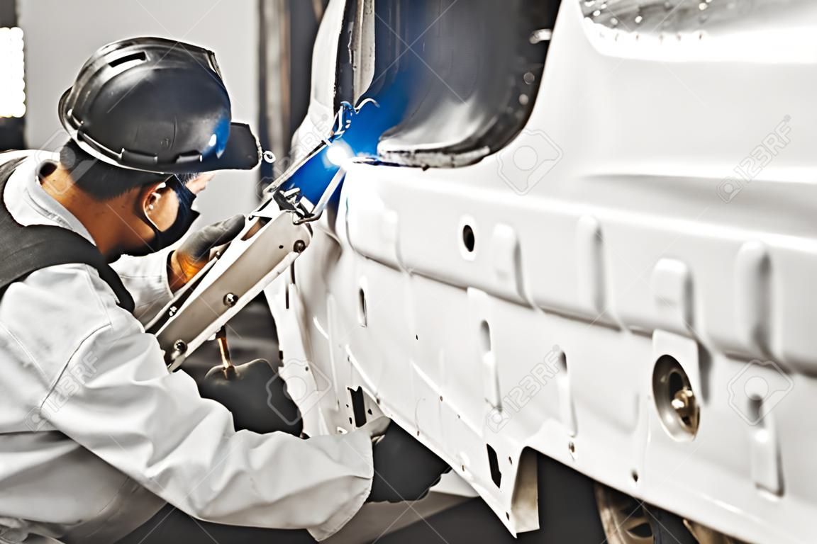 Trabalhador que repara o corpo do carro com soldadura do dióxido de carbono. Solda do automóvel.