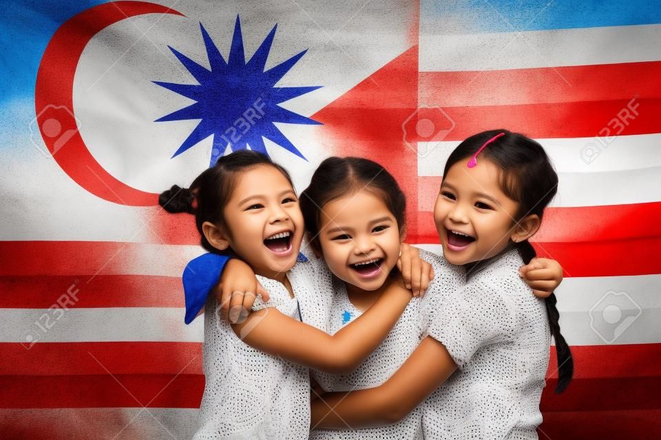 Happy girls étreindre les uns les autres avec le drapeau de la Malaisie dans le fond