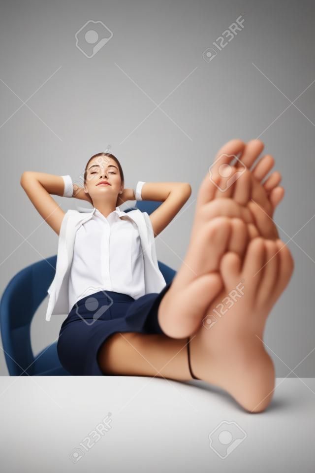 Businesswoman resting with her legs up on a table and hands behind her head