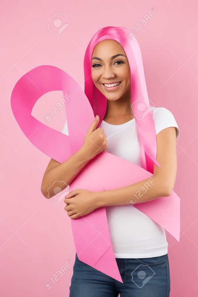 Frau lächelt, während mit einem rosa Brustkrebs Band