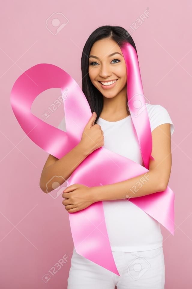 Frau lächelt, während mit einem rosa Brustkrebs Band