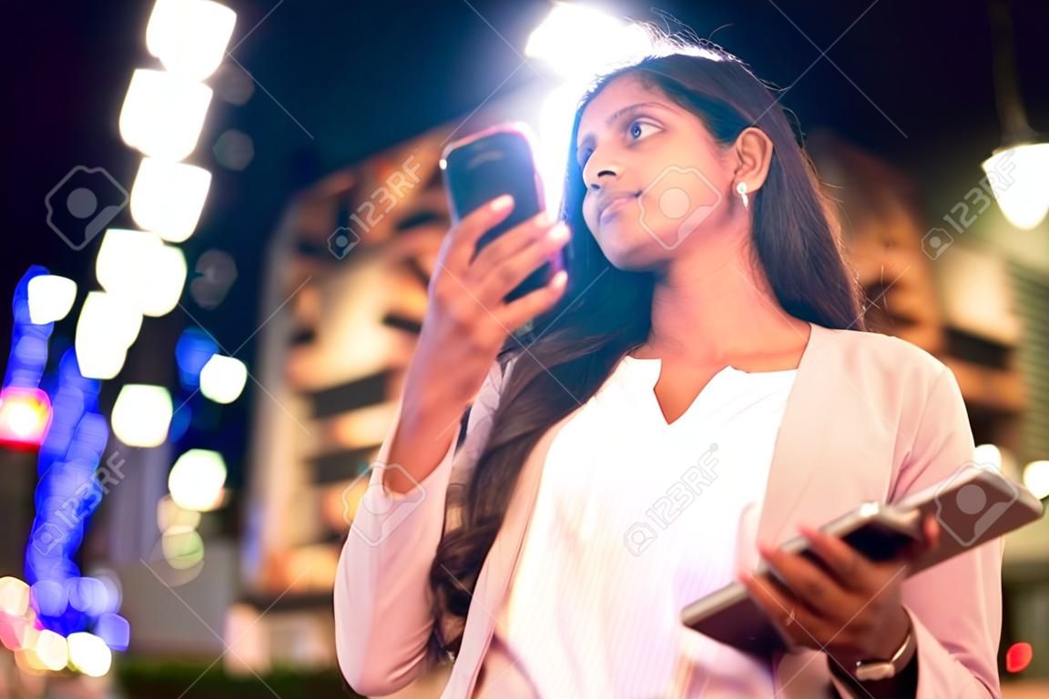 Jovem indiana com telefone celular em uma cidade